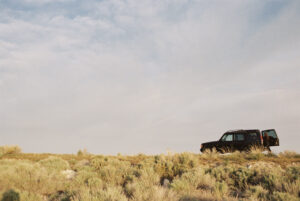 A person standing by the open rear door of a 4x4 vehicle.