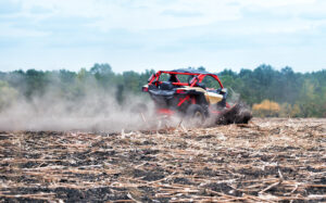 Red buggy rushes through the field in the dust